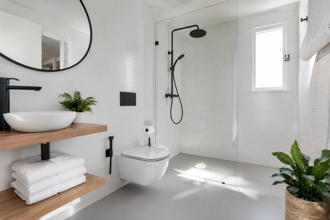 Baño de habitación de hotel renovado con esmalte epoxi blanco, ducha a ras de suelo y acabado moderno
