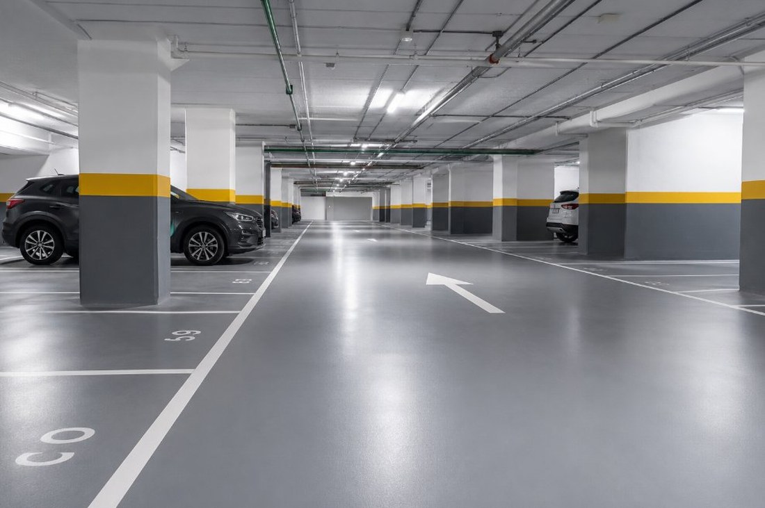 Garaje subterráneo de un complejo residencial turístico de Salou con pavimento epoxi gris y plazas numeradas