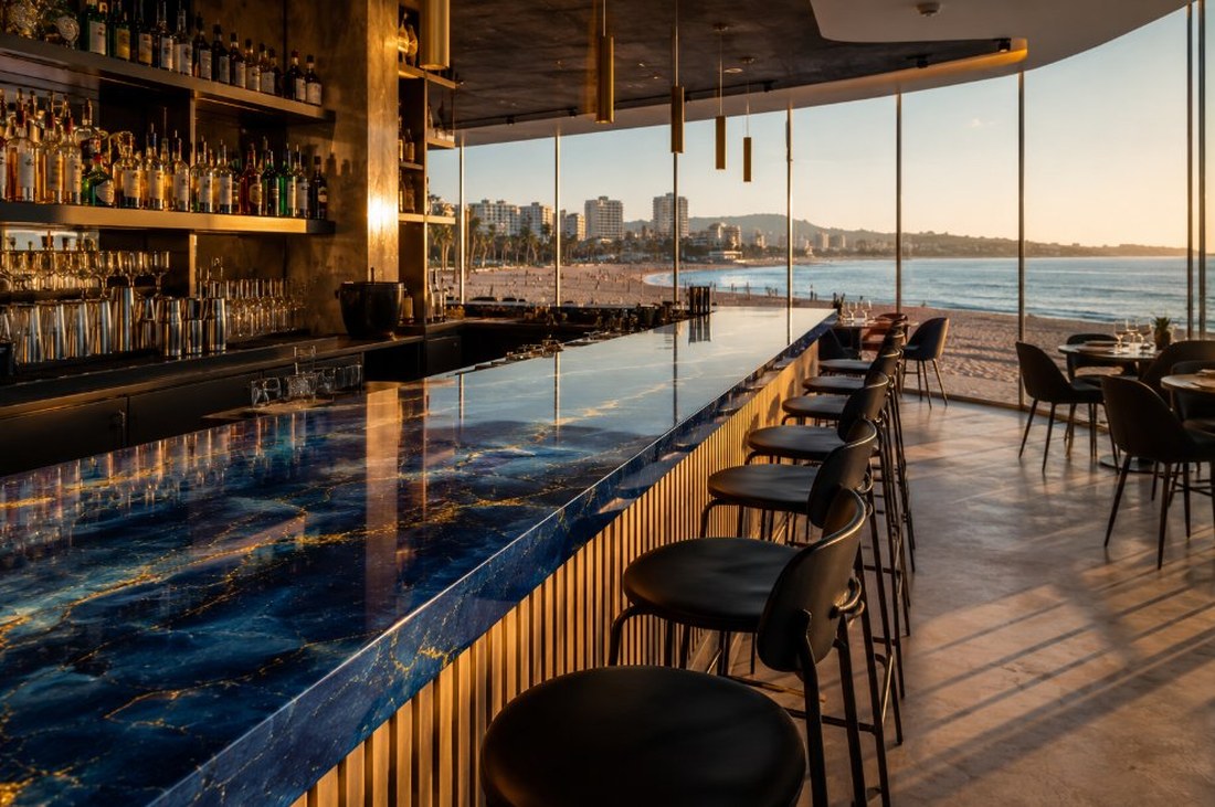 Barra de restaurante rematada con resina epoxi azul profundo y vetas doradas frente a un ventanal con vista al mar