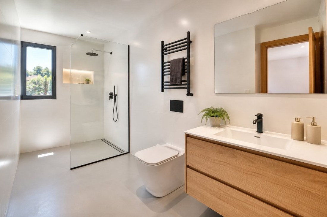 Baño de piso renovado con esmalte epoxi blanco, ducha a ras de suelo con mampara y mueble de madera